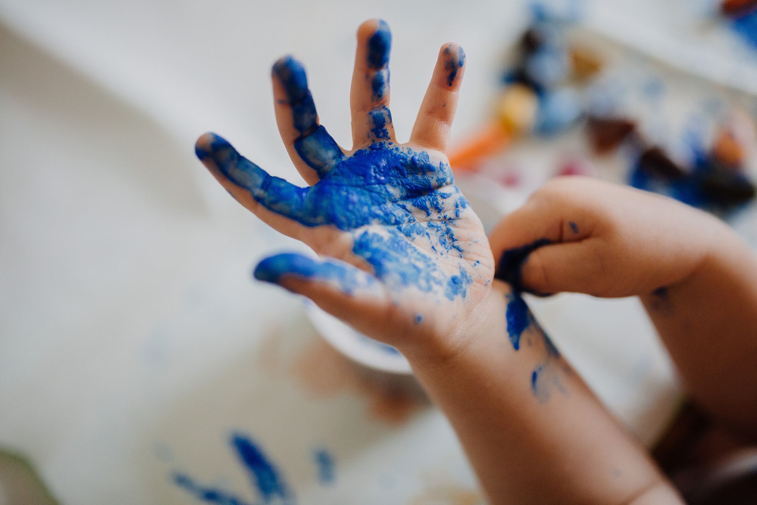 A kid painting with blue paint