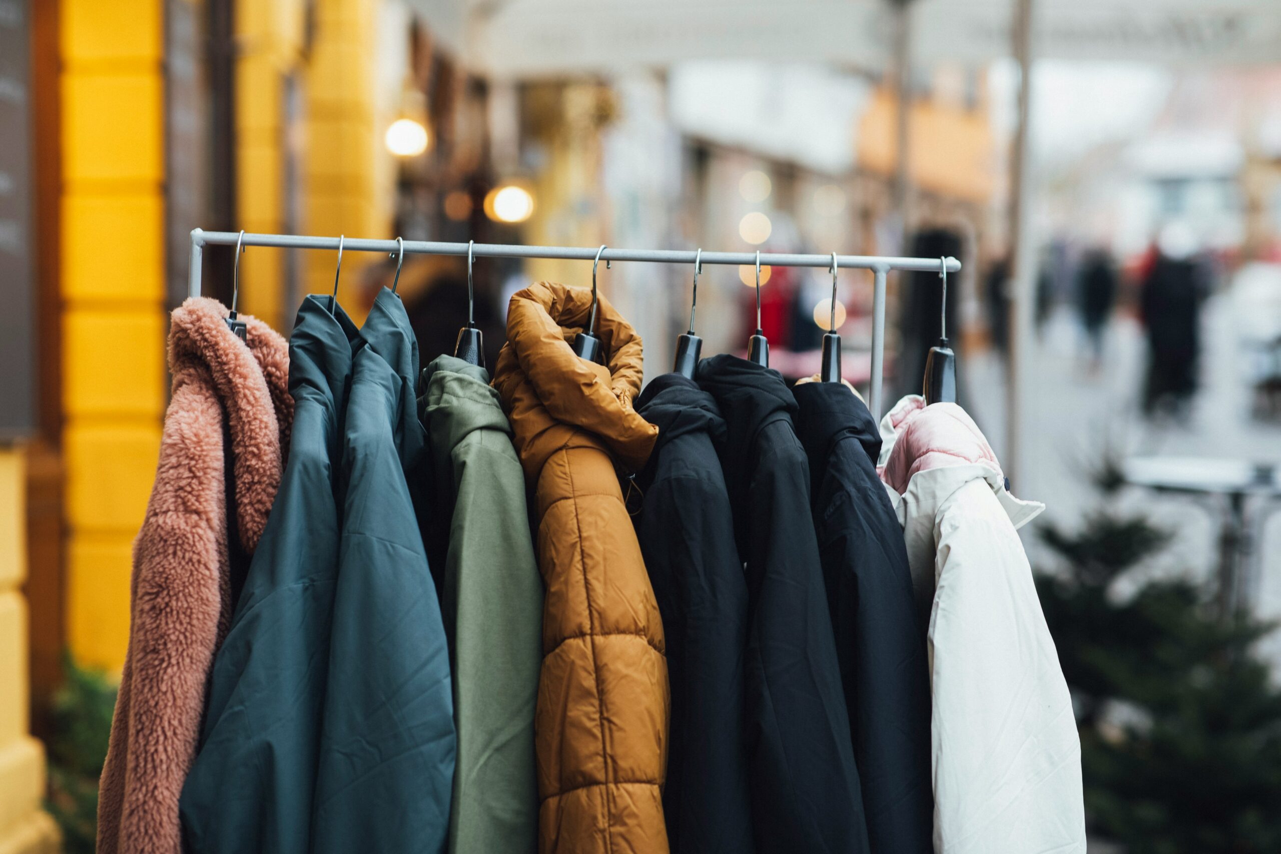 A variety of winter coats are hanging on a rack. 